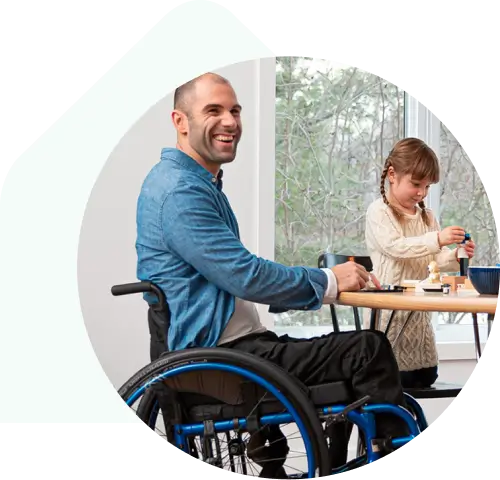 Man in a wheelchair smiling and sitting at table with child