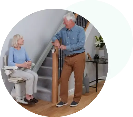 Women in stairlift talking to man standing in hallway