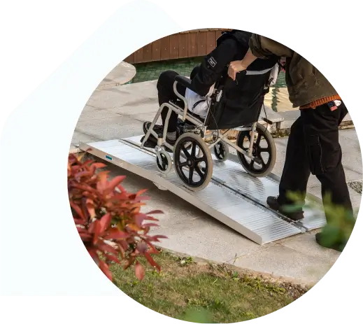 Person pushing another person in a manual wheelchair up a temporary ramp